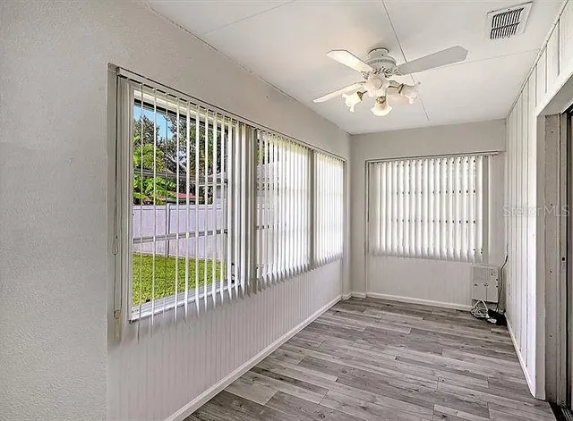 a view of an empty room with wooden floor and a window