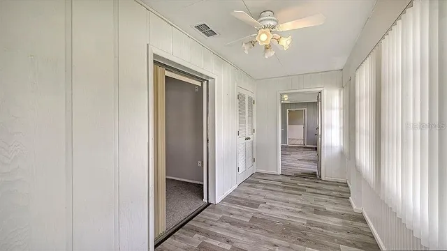 a view of a hallway with a chandelier fan and closet