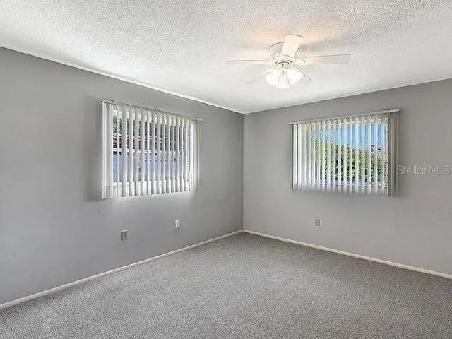 an empty room with windows and fan
