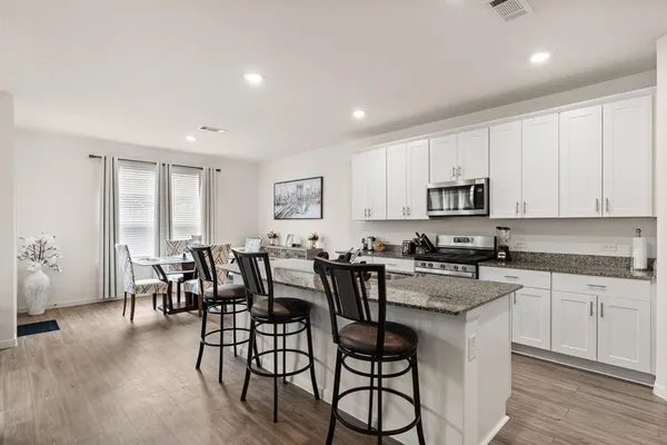 a kitchen with stainless steel appliances granite countertop a table and chairs in it