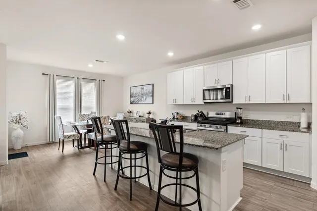 a kitchen with stainless steel appliances granite countertop a table and chairs in it