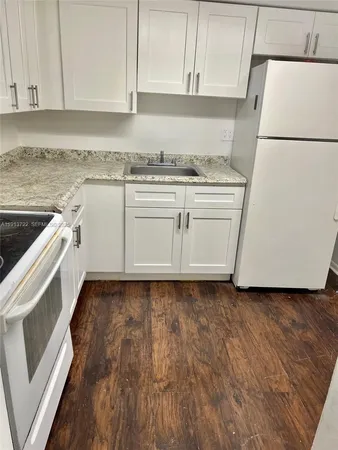 a kitchen with granite countertop white cabinets and white appliances