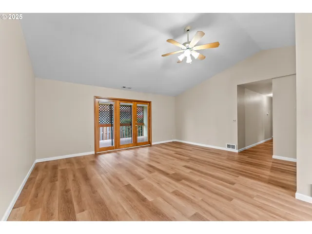 a view of an empty room with window and wooden floor