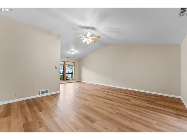 a view of an empty room with a window and wooden floor