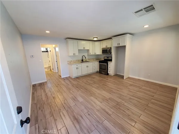 a large kitchen with a wooden floor and stainless steel appliances