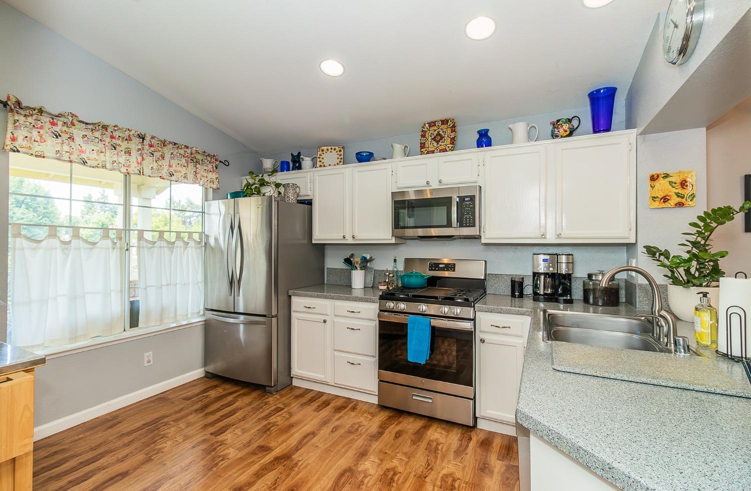 2831 Purvis Avenue Clovis, CA 93611 - Photo 9 of 26 a kitchen with granite countertop a refrigerator a stove a sink and white cabinets with wooden floor