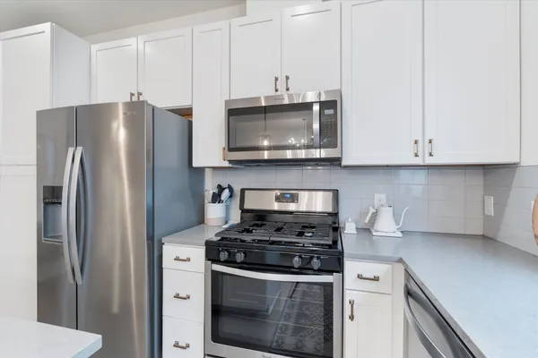a kitchen with stainless steel appliances granite countertop a stove a refrigerator and a microwave