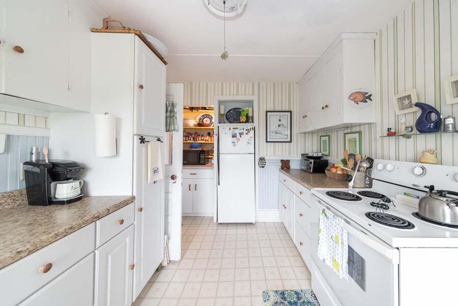 139 Shore Road Truro, MA 02666 - Photo 19 of 30 a kitchen with stainless steel appliances a stove a sink a refrigerator white cabinets and dining table
