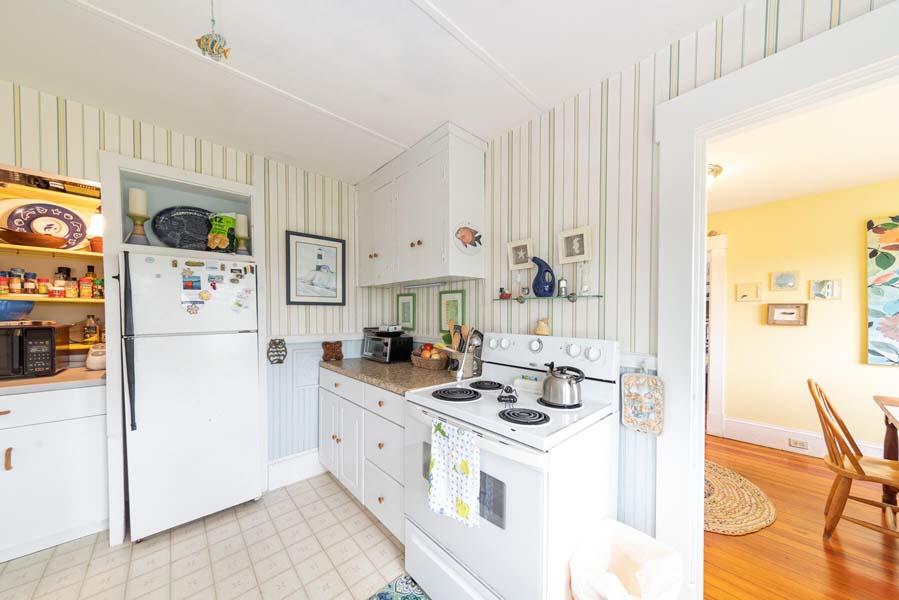 139 Shore Road Truro, MA 02666 - Photo 20 of 30 a kitchen with stainless steel appliances a white refrigerator a stove a sink and white cabinets with wooden floor
