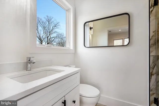 a bathroom with a toilet sink vanity and mirror