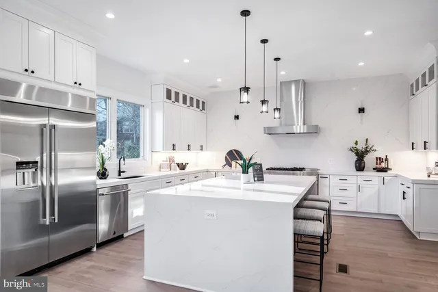 a kitchen with stainless steel appliances granite countertop a sink a stove a refrigerator and island with wooden floor