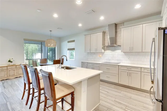 a kitchen with stainless steel appliances granite countertop a table chairs sink refrigerator and cabinets
