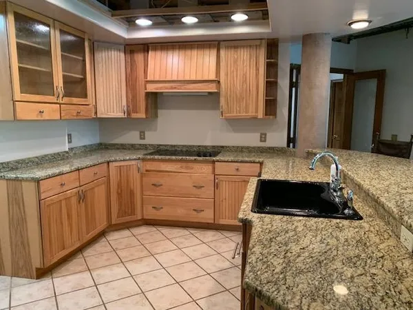 a large kitchen with granite countertop a sink and cabinets