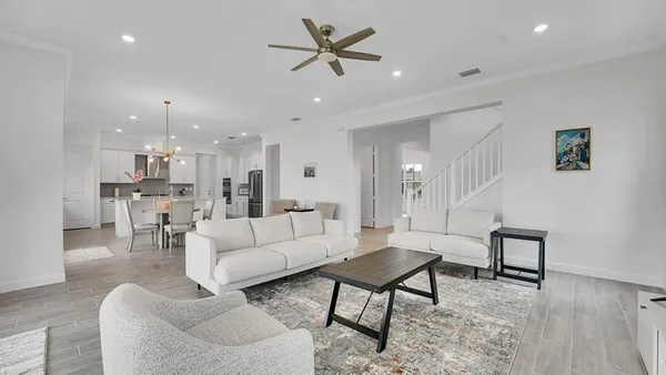 a living room with furniture kitchen view and a chandelier