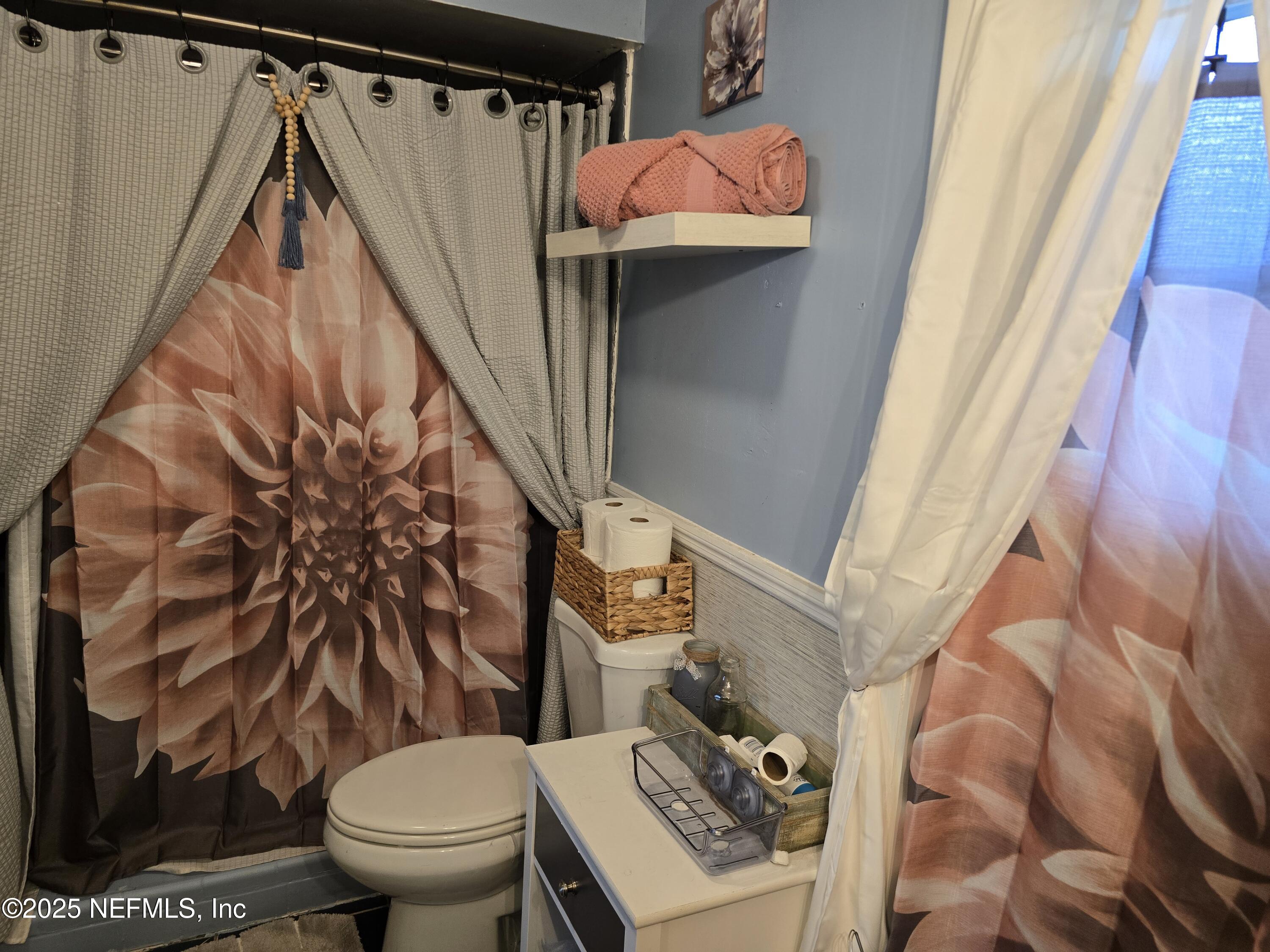 6051 Foxfire Court Jacksonville, FL 32244 - Photo 15 of 31 a bathroom with a toilet and a shower curtain
