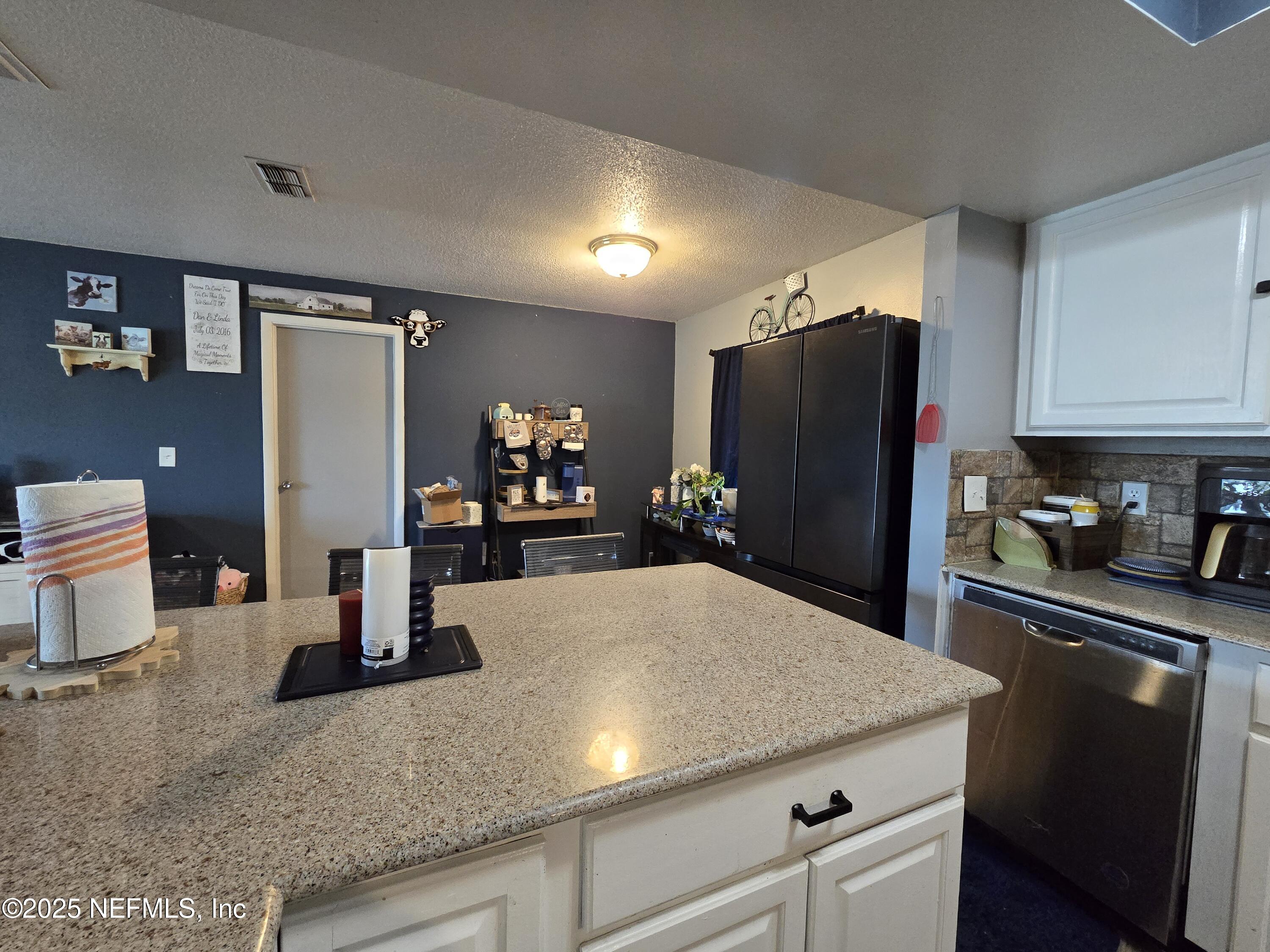 6051 Foxfire Court Jacksonville, FL 32244 - Photo 9 of 31 a kitchen with stainless steel appliances kitchen island granite countertop a refrigerator a stove a sink a washer and island