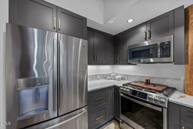 a kitchen with stainless steel appliances granite countertop a refrigerator a stove and a sink with wooden floor