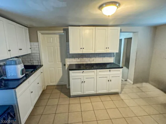 a kitchen with granite countertop white cabinets and stainless steel appliances