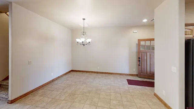 an empty room with chandelier fan and windows