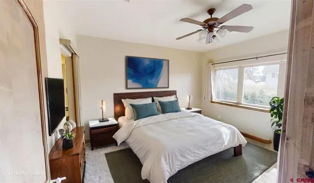 a bedroom with a bed a ceiling fan and a window
