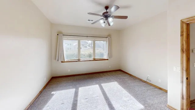 an empty room with chandelier fan and windows