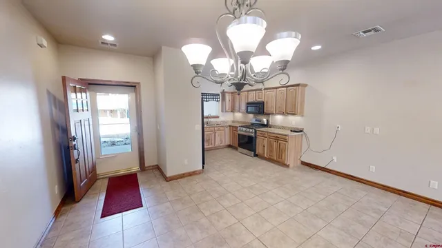 a kitchen with stainless steel appliances granite countertop a refrigerator a sink dishwasher a stove and a dining table with wooden floor