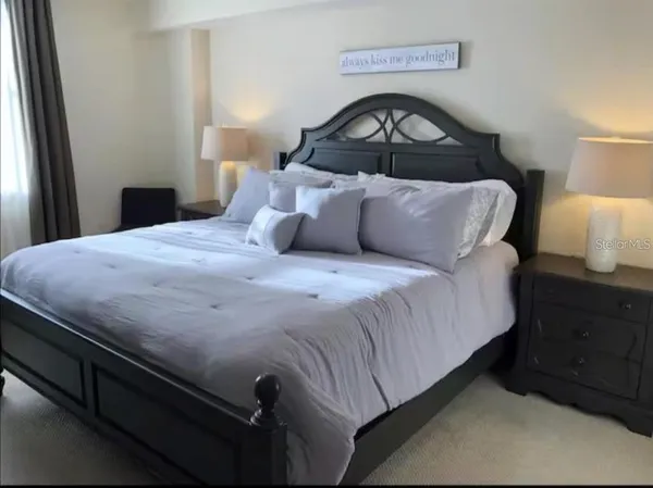 a bedroom with a bed and a lamp on dresser