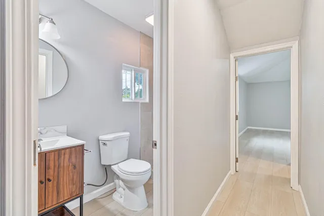 a white toilet sitting next to a bathroom sink and a mirror