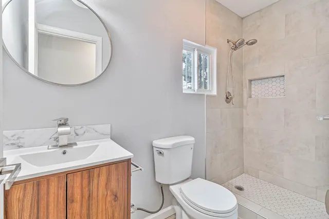 a bathroom with a toilet a sink a mirror and vanity