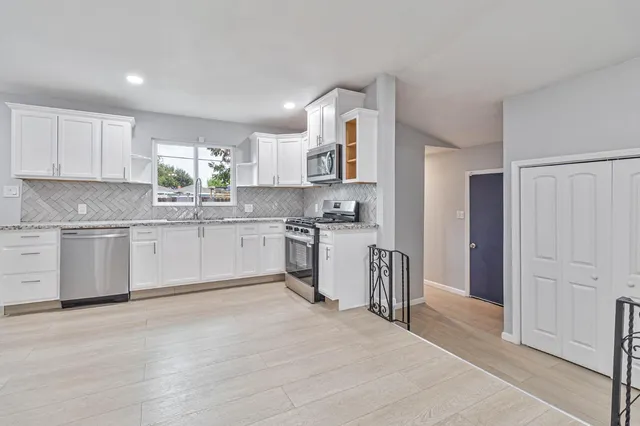 a kitchen with granite countertop a sink cabinets stainless steel appliances and a window