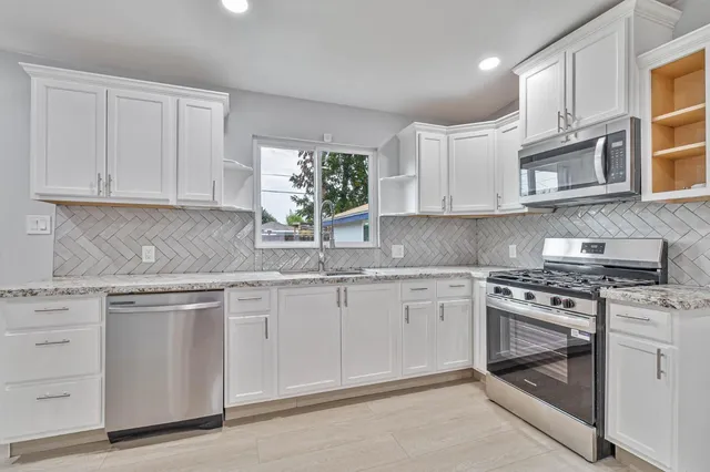 a kitchen with granite countertop white cabinets and white stainless steel appliances