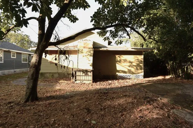 a view of a backyard with large trees and wooden fence