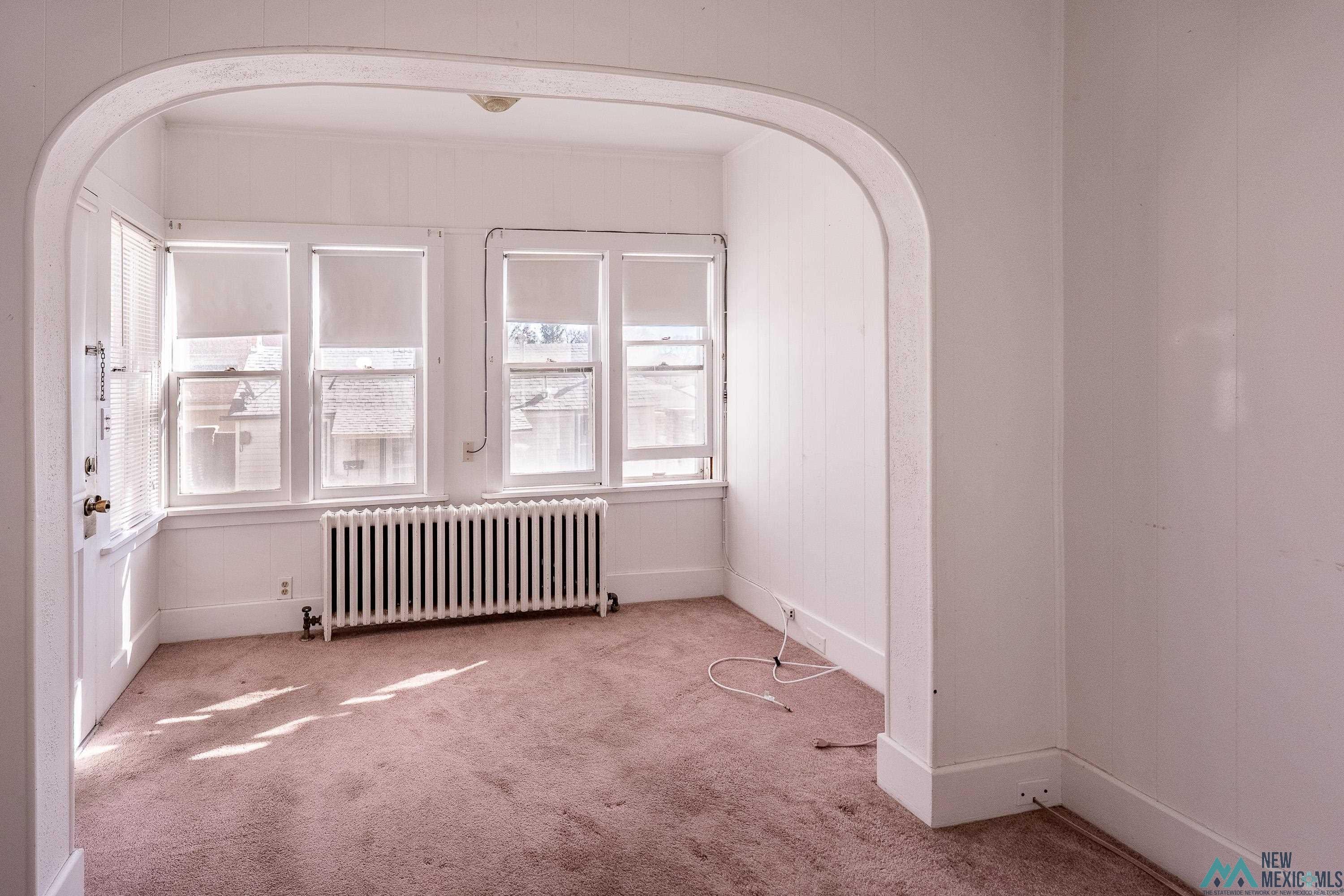301 South 4th Street Raton, NM 87740 - Photo 59 of 78 Empty room with radiator heating unit, carpet flooring, and arched walkways