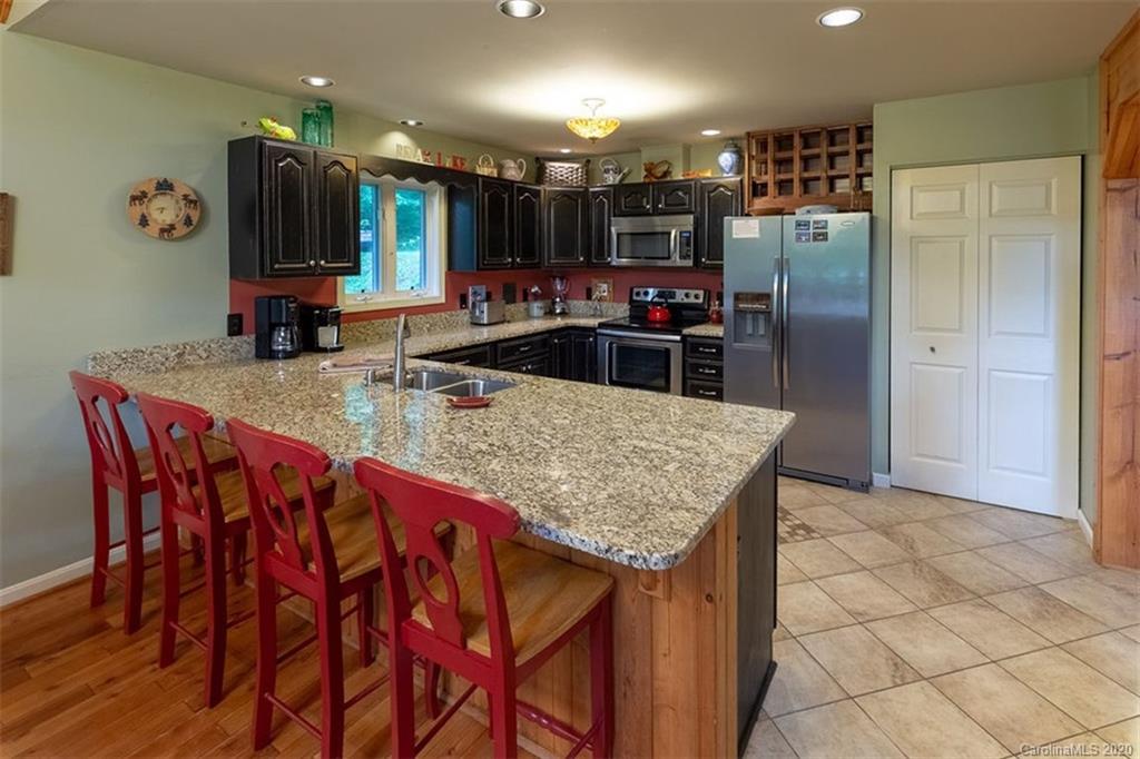 136 Dars Lane Tuckasegee, NC 28783 - Photo 15 of 48 a kitchen with stainless steel appliances granite countertop a table chairs sink refrigerator and microwave