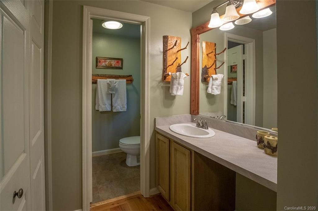 136 Dars Lane Tuckasegee, NC 28783 - Photo 18 of 48 a bathroom with a granite countertop sink a toilet a mirror and shower