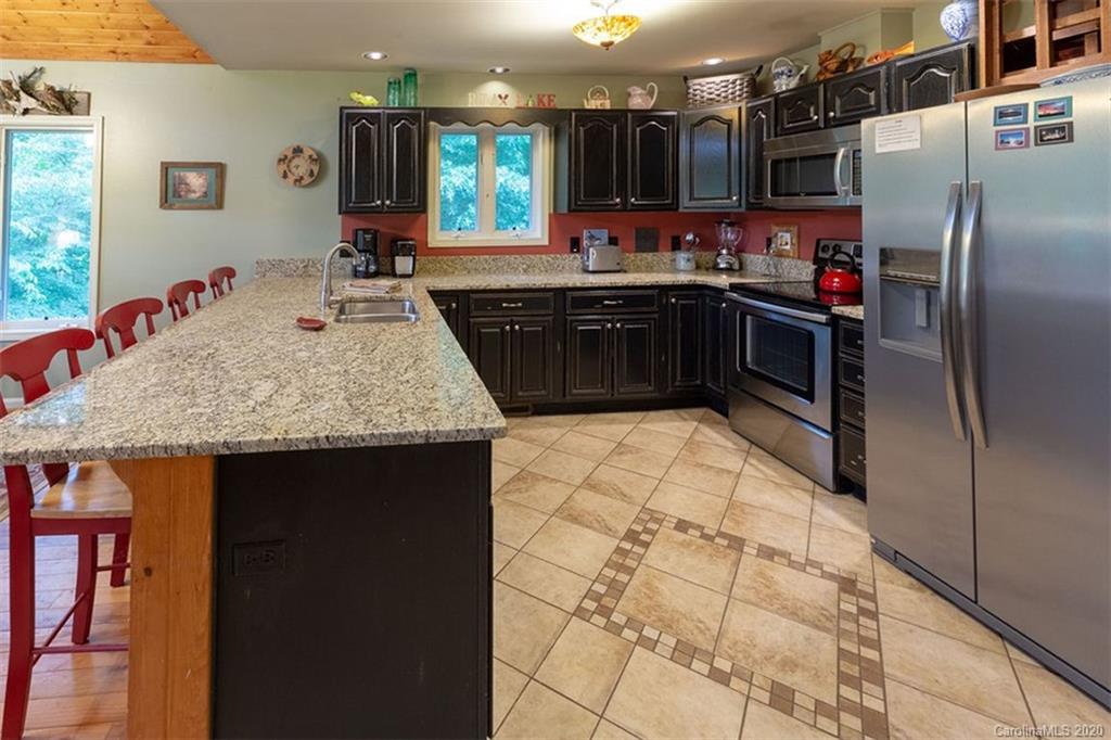 136 Dars Lane Tuckasegee, NC 28783 - Photo 9 of 48 a kitchen with stainless steel appliances granite countertop a sink wooden cabinets and granite counter tops