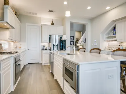 a kitchen with white cabinets a sink dishwasher and a stove with wooden floor