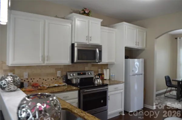 a kitchen with stainless steel appliances granite countertop a refrigerator stove and white cabinets