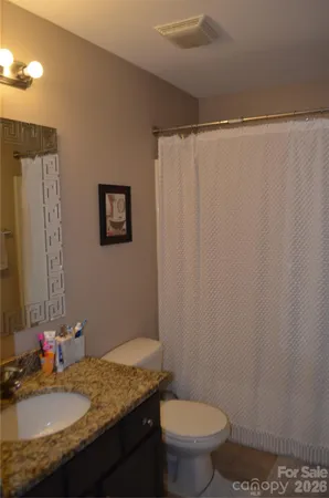 a bathroom with a granite countertop sink toilet and a mirror