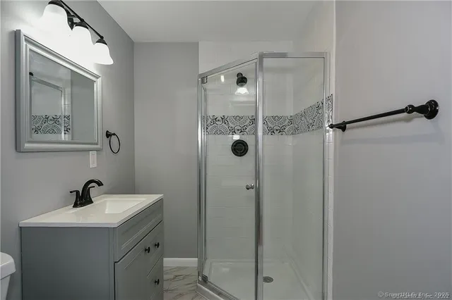 a bathroom with a shower sink vanity and toilet