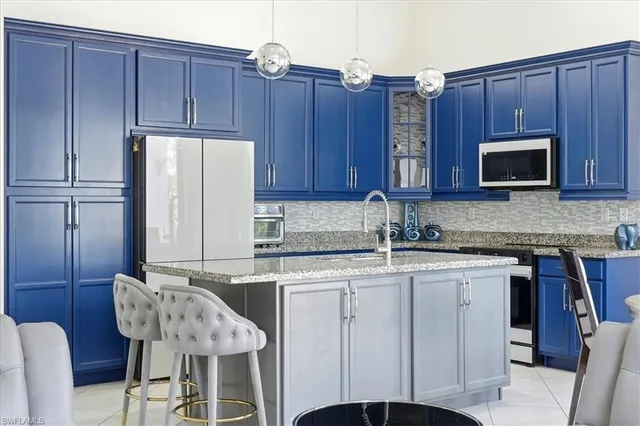 a kitchen with stainless steel appliances granite countertop a table chairs microwave and sink