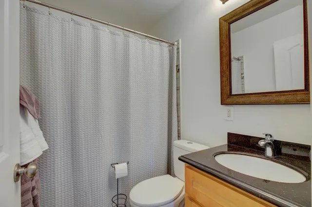 a bathroom with a granite countertop sink toilet and mirror
