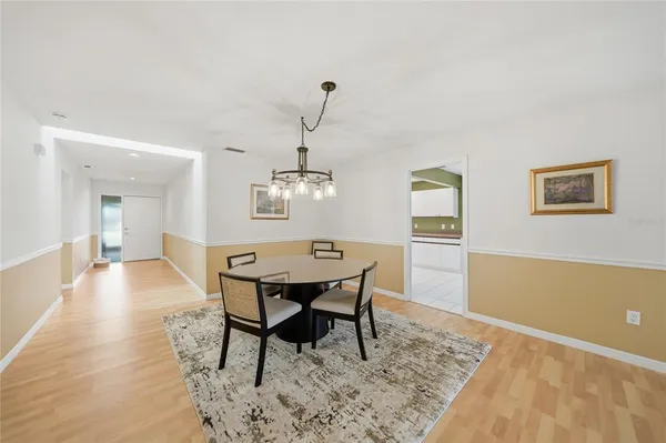 a dining room with wooden floor a chandelier a wooden table and chairs