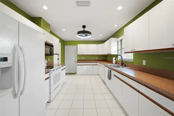 a large white kitchen with a large window and stainless steel appliances