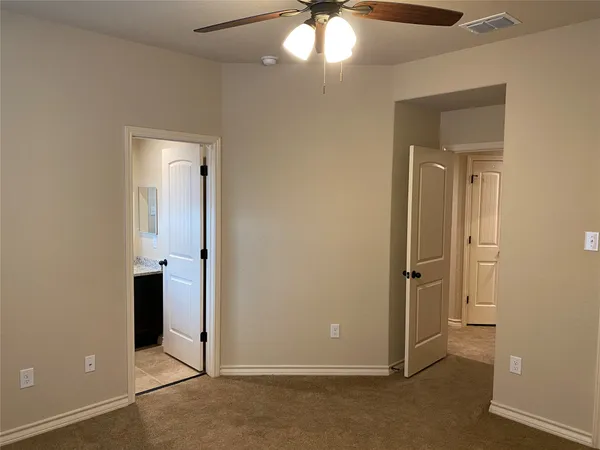 an empty room with a chandelier fan and closet