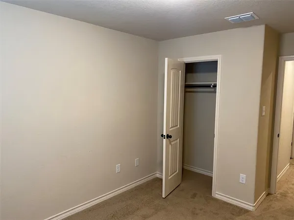 an empty room with closet and a ceiling fan