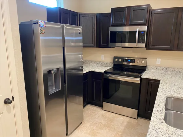 a kitchen with granite countertop a refrigerator stove and microwave