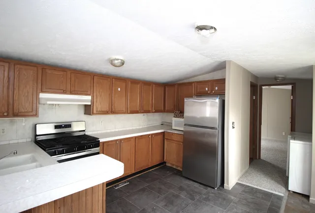 a kitchen with stainless steel appliances a refrigerator a sink and white cabinets