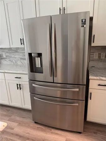 a close view of a refrigerator a stove and wooden floor
