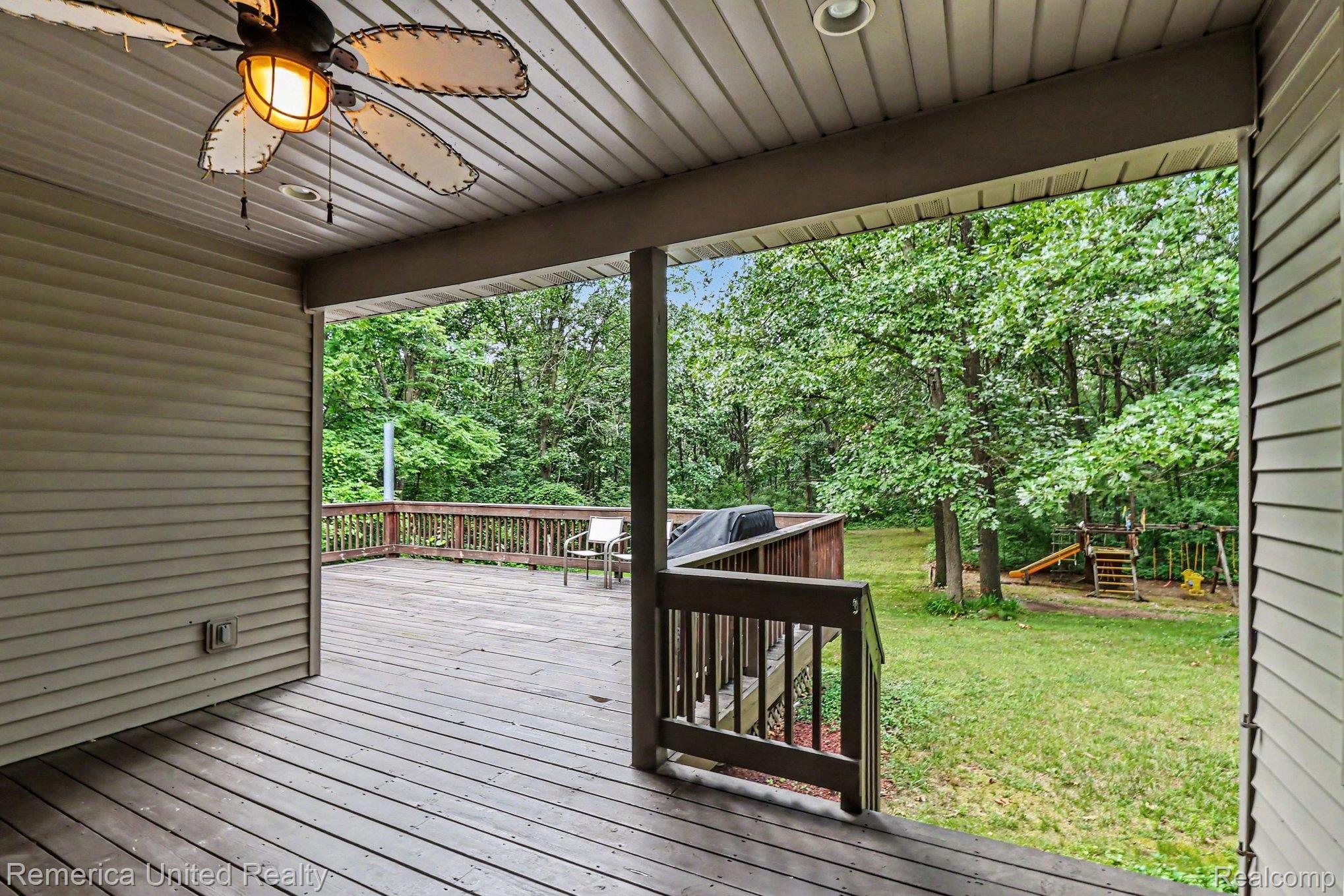 20962 Wasson Road Gregory, MI 48137 - Photo 33 of 39 Expansive outdoor deck space featuring wood decking and railings, a covered section with a ceiling fan, and recessed lighting